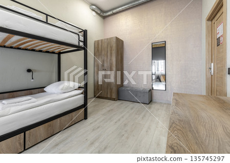 Hostel dormitory room with black metal bunk bed and wooden wardrobe 135745297