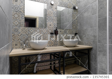 Modern hostel shared bathroom with double vessel sinks and patterned tiles 135745301
