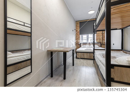 Hostel dormitory with industrial bunk beds and large wall mirror 135745304