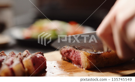 man slicing new york steak on olive wood board man slicing new york steak on olive wood board 135745549