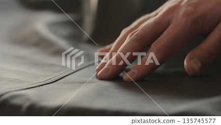 closeup man hand checking seam on soft gray leather clothes closeup man hand checking seam on soft gray leather clothes 135745577