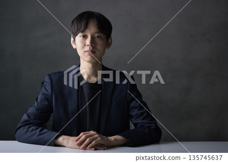 A man in his 20s with a serious expression looking straight at the camera 135745637