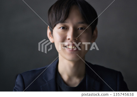 一名二十多歲的男子對著鏡頭微笑 一名二十多歲的男子對著鏡頭微笑 135745638