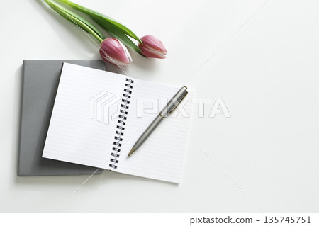 Flat lay of an open notebook, pen and tulips on a desk with a white background (copy space) 135745751