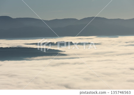 The image shows a serene mountain landscape above a sea of clouds. 135746563