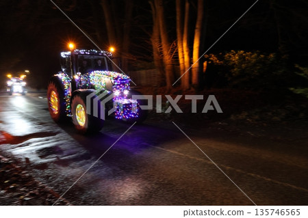 A tractor is decorated with lights and is driving down a road 135746565
