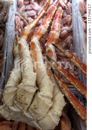 Crab claws rest on ice alongside shrimp at a market. Workers prepare seafood for customers during busy trading hours in this commercial space Crab claws rest on ice alongside shrimp at a market. Workers prepare seafood for customers during busy trading hours in this commercial space 135746617