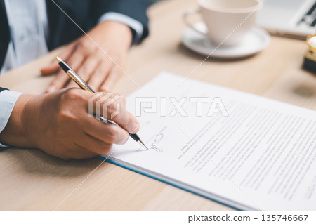 Lawyer in suit signing a contract on clipboard at office desk with justice scales in background, representing legal services, compliance review, agreement approval and documentation. Lawyer in suit signing a contract on clipboard at office desk with justice scales in background, representing legal services, compliance review, agreement approval and documentation. 135746667