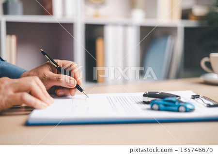 Person signing auto loan agreement on clipboard with car keys and calculator on desk, completing vehicle purchase paperwork, financing approval, insurance details and budget planning. Person signing auto loan agreement on clipboard with car keys and calculator on desk, completing vehicle purchase paperwork, financing approval, insurance details and budget planning. 135746670