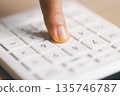 Macro close-up of a finger pressing white calculator keys, performing quick calculations for budgeting, accounting, tax and expense tracking in office or home finance, soft light, shallow focus. 135746787