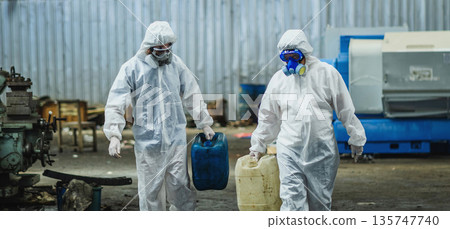 Two people in hazmat suits are carrying blue and white containers Two people in hazmat suits are carrying blue and white containers 135747740