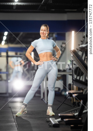 Fit woman standing in gym showing strong abs 135747772