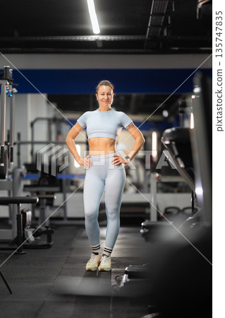 Fit woman standing in gym showing strong body Fit woman standing in gym showing strong body 135747835