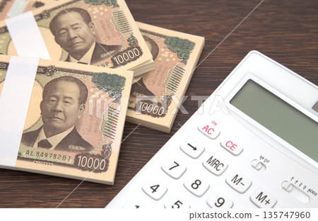 Money and a calculator on a desk Money and a calculator on a desk 135747960