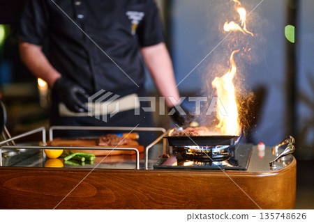 Professional Chef Grilling On a Portable Stove With Dramatic Fire While Cooking Fresh Food Professional Chef Grilling On a Portable Stove With Dramatic Fire While Cooking Fresh Food 135748626