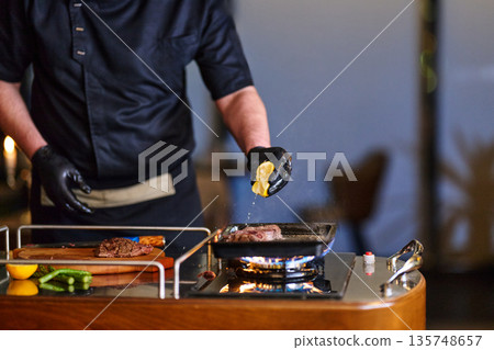 Chef Grilling Steak On Gas Stove Grill With Lemon Wedge And Sizzling Pan Fire Chef Grilling Steak On Gas Stove Grill With Lemon Wedge And Sizzling Pan Fire 135748657