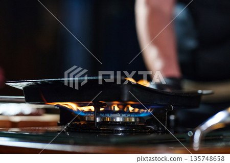 Close Up Of Gas Stove Flame With Skillet On Pan In Modern Kitchen Setting 135748658