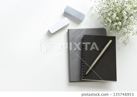 筆記本、鋼筆、橡皮擦和滿天星平鋪在白色背景的桌子上（留有文字空間） 135748953