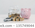 Pink piggy bank with coin jar, stacked coins and toy car on white background, symbolizing car savings, down payment goals, auto loan budgeting and personal finance planning. 135749044