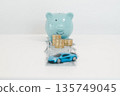 Blue piggy bank with stacked coins on dollar bills and toy car on white background, representing car savings, down payment budgeting, auto loan planning and financial goals with copy space. 135749045