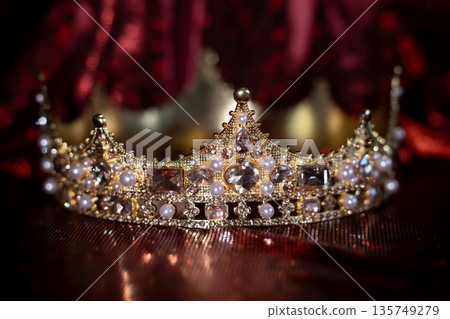 Ancient golden medieval crown with gemstones on sparkle red background. Ancient golden medieval crown with gemstones on sparkle red background. 135749279