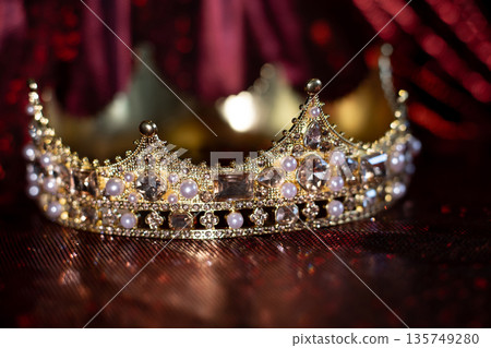 Ancient golden medieval crown with gemstones on sparkle red background. Ancient golden medieval crown with gemstones on sparkle red background. 135749280