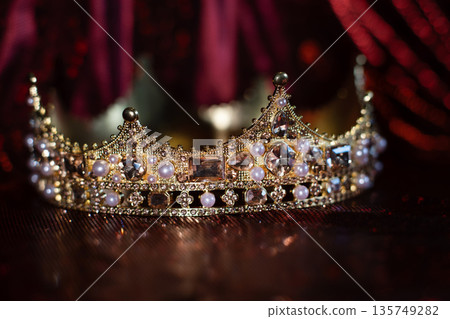 Ancient golden medieval crown with gemstones on sparkle red background. Ancient golden medieval crown with gemstones on sparkle red background. 135749282