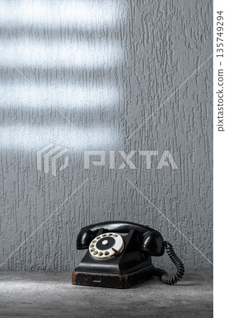 Vintage black telephone with rotary dial on gray stone table. Vintage black telephone with rotary dial on gray stone table. 135749294