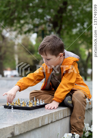 Boy playing chess outdoor. Learning strategic game. Education. Boy playing chess outdoor. Learning strategic game. Education. 135749399