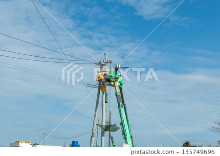 Workers working at height on a telephone pole, blue sky and power company workers 135749696