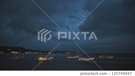 Boats resting on the shore under a dramatic twilight sky Boats resting on the shore under a dramatic twilight sky 135749947