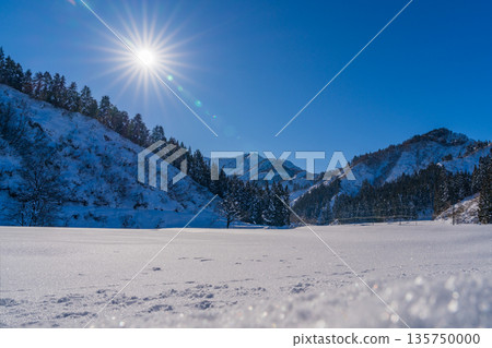 廣闊的雪原和連綿的山脈在晴朗的冬日天空下閃閃發光，銀色的山巒在耀眼的陽光下閃閃發光。 135750000