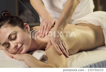 Calming spa session with therapist massaging womans shoulder for stress relief 135750233