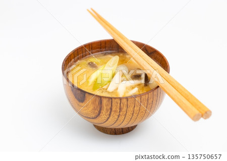 Miso soup with mushrooms and green onions. Photo on a white background. Shimeji mushroom miso soup in a wooden bowl. 135750657