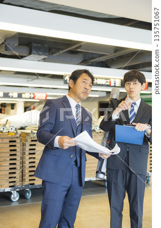 A middle-aged man in a suit managing the event A middle-aged man in a suit managing the event 135751067