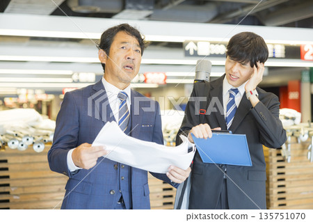 A middle-aged man in a suit managing the event A middle-aged man in a suit managing the event 135751070