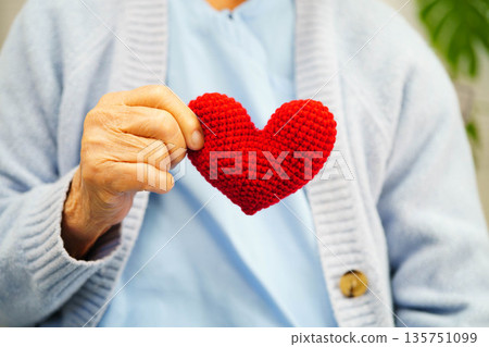 Asian elder senior woman patient holding red heart in hospital. 135751099