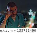 Medical professional wearing scrubs and glasses at night 135751490