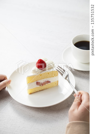 Woman's hand eating strawberry shortcake 135751532