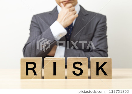 A block with the word "RISK" written on it and a businessman A block with the word "RISK" written on it and a businessman 135751803