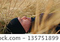 A Tranquil Moment of Solitude: A Man Resting in a Golden Field Surrounded by Tall Grass, Capturing Peaceful Connection with Nature and the Beauty of the Outdoors 135751899
