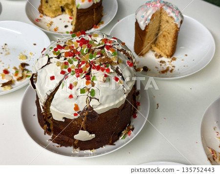 Traditional Easter cakes topped with white icing, colorful candied fruit are arranged on plates, bright accents contrast with golden baked texture Traditional Easter cakes topped with white icing, colorful candied fruit are arranged on plates, bright accents contrast with golden baked texture 135752443