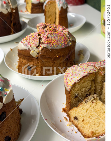 Traditional Easter cakes with white icing, colorful sprinkles, raisins are arranged on plates, sliced pieces reveal soft crumb, festive texture Traditional Easter cakes with white icing, colorful sprinkles, raisins are arranged on plates, sliced pieces reveal soft crumb, festive texture 135752451