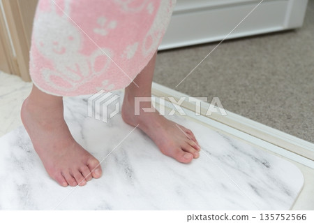 A girl wiping her feet on a diatomaceous earth bath mat 135752566