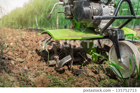 Farmer with ploughs ground in sunny day.  preparing land with seedbed cultivator as part of pre seeding activities in early spring season of agricultural works at farmlands. 135752713