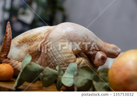 Whole raw turkey ready for cooking on a wooden table. Uncooked poultry for a festive meal. Holiday food preparation for Thanksgiving or Christmas. 135753032