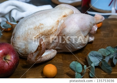 Raw whole chicken on a wood cutting board, ready for cooking a festive meal. Fresh poultry preparation for Thanksgiving or Christmas dinner. 135753036