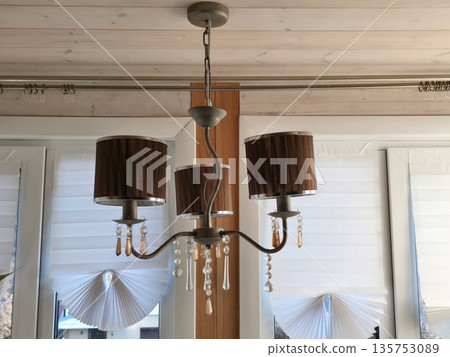 Rustic chandelier with three fabric shades and crystal elements. Home interior lighting fixture with decorative design. Elegant ceiling lamp. Rustic chandelier with three fabric shades and crystal elements. Home interior lighting fixture with decorative design. Elegant ceiling lamp. 135753089
