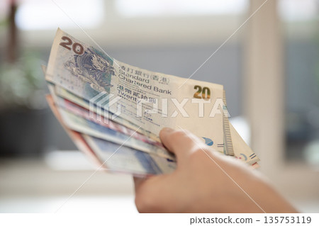Woman holding Hong Kong twenty dollar banknotes. Financial transaction concept. Currency exchange and travel budget planning. Woman holding Hong Kong twenty dollar banknotes. Financial transaction concept. Currency exchange and travel budget planning. 135753119