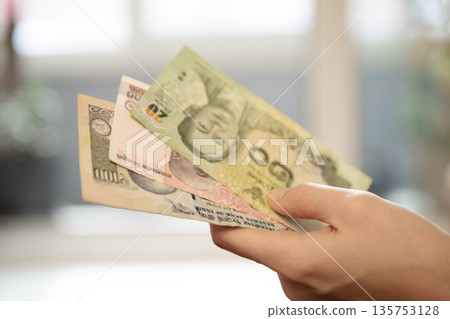 Woman s hand holding variety of international currency banknotes. Concept of travel budget, foreign exchange, or global finance for business. Woman s hand holding variety of international currency banknotes. Concept of travel budget, foreign exchange, or global finance for business. 135753128